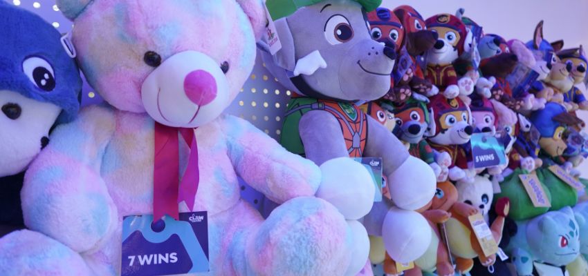 Colourful plush toys and teddy bears displayed on the Prize Wall at Claw Culture